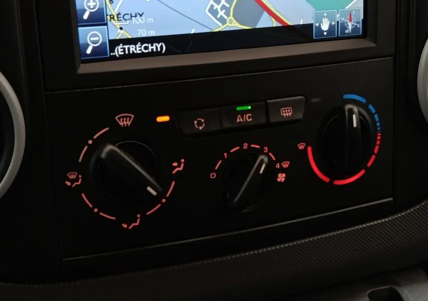 Gros plan sur la console de climatisation et l’écran de navigation du Peugeot Partner blanc, version 1.6 BlueHDi 2018.