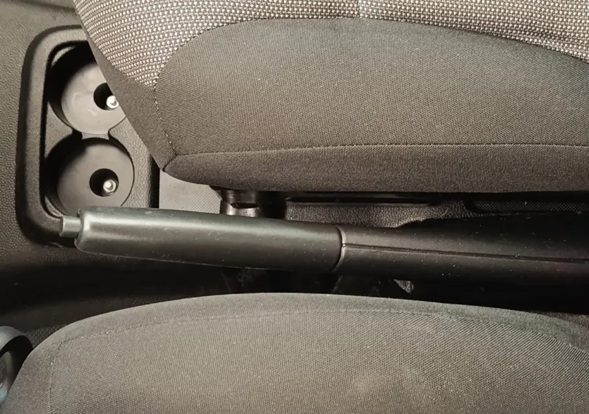 Vue rapprochée de la poignée de frein à main entre les sièges avant gris foncé d’un Peugeot Partner blanc.
