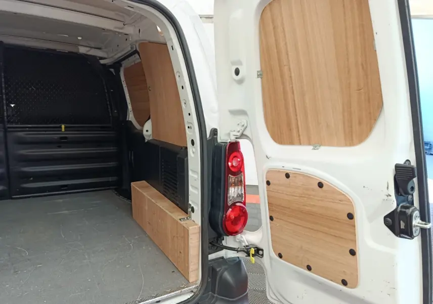 Intérieur arrière du Peugeot Partner blanc 2018, vue porte ouverte avec cloison bois et espace de chargement visible.