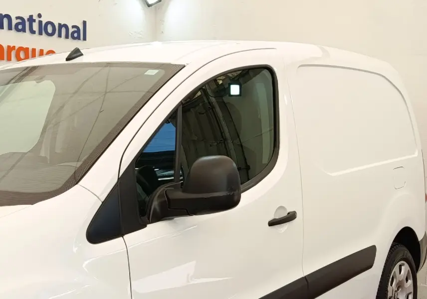 Vue 3/4 avant droit du Peugeot Partner 1.6 BlueHDi 100 Long Pro blanc avec rétroviseur noir et protections latérales noires.