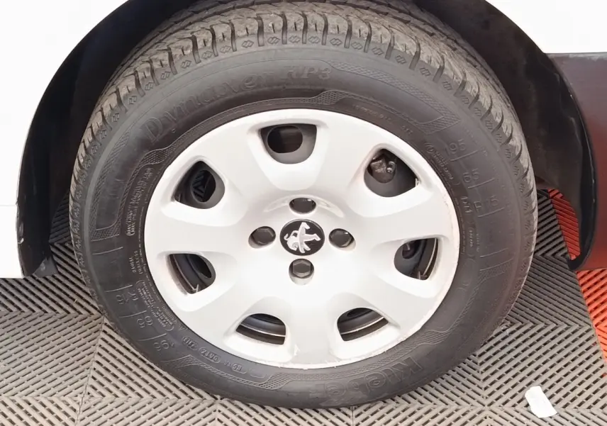 Gros plan sur la roue avant gauche blanche d’un Peugeot Partner 1.6 BlueHDi 100 Long Pro de 2018.