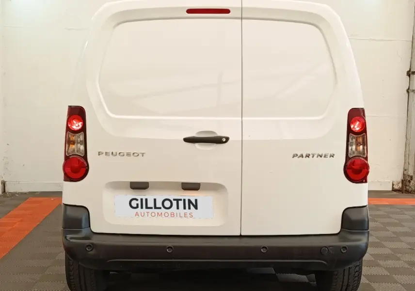 Vue arrière d'un Peugeot Partner blanc 2018 avec portes battantes et feux arrière allumés dans un garage.