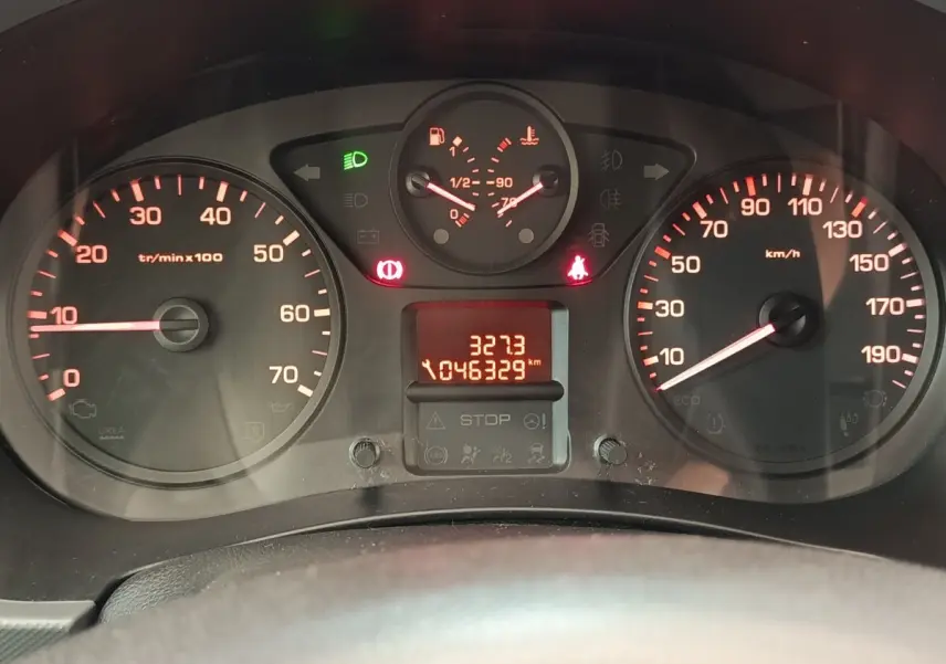 Vue rapprochée du tableau de bord du Peugeot Partner blanc, affichant compteur et témoins lumineux rouges et verts.