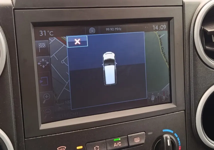 Écran de navigation intérieur montrant une vue en plan du Peugeot Partner blanc, tableau de bord et commandes climatisation visibles.
