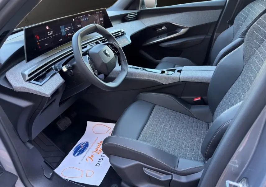 Intérieur avant droit du Peugeot 3008 gris clair 2025, avec tableau de bord numérique et sièges tissu-cuir bicolores.