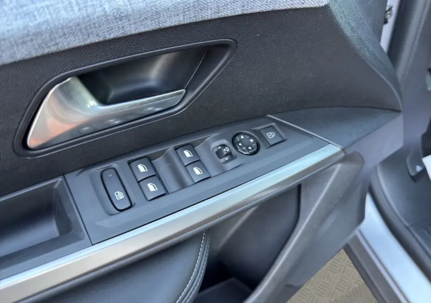 Gros plan sur la porte côté conducteur du Peugeot 3008 gris clair, montrant les commandes des vitres et rétroviseurs.