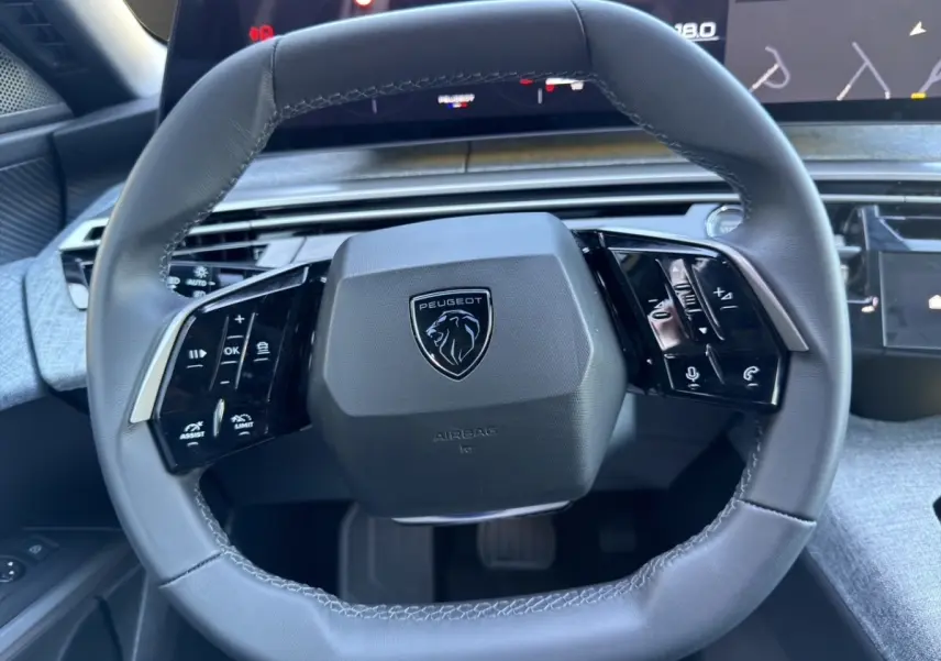 Vue rapprochée du volant cuir noir du Peugeot 3008 2025 avec commandes multifonctions et logo lion central.