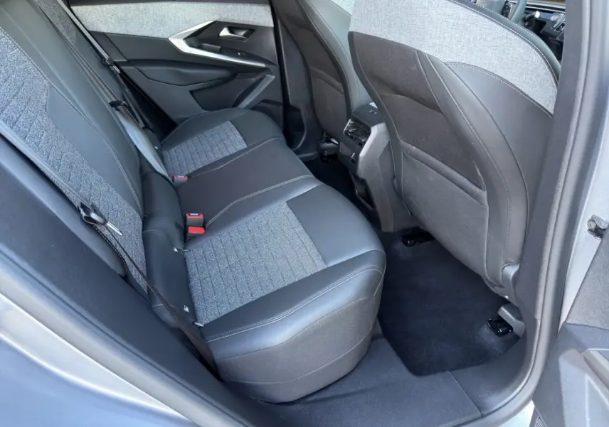 Vue intérieure arrière côté gauche du Peugeot 3008 2025 gris clair, montrant la banquette mixte tissu et cuir.