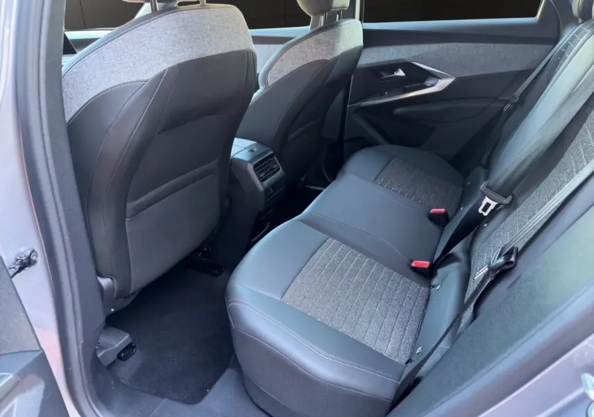 Vue intérieure côté arrière droit du Peugeot 3008 gris clair, montrant la banquette arrière en tissu et cuir avec ceintures de sécurité.