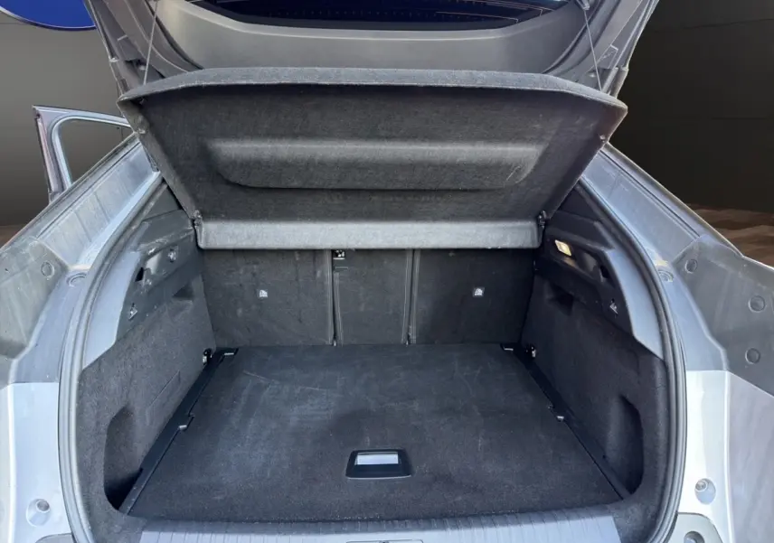 Coffre ouvert vu de l'arrière d'un Peugeot 3008 gris clair, montrant un espace de chargement spacieux et propre.