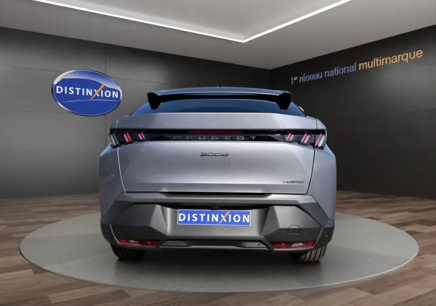 Vue arrière d'un Peugeot 3008 hybride gris clair avec feux LED distinctifs et toit panoramique en showroom.