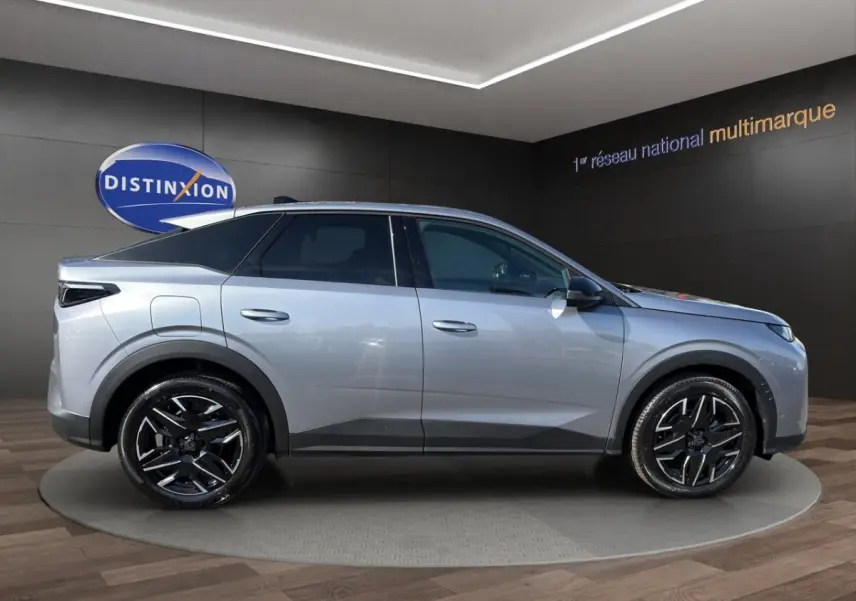Vue de profil côté droit d’un Peugeot 3008 gris clair avec jantes noires et toit panoramique en showroom.