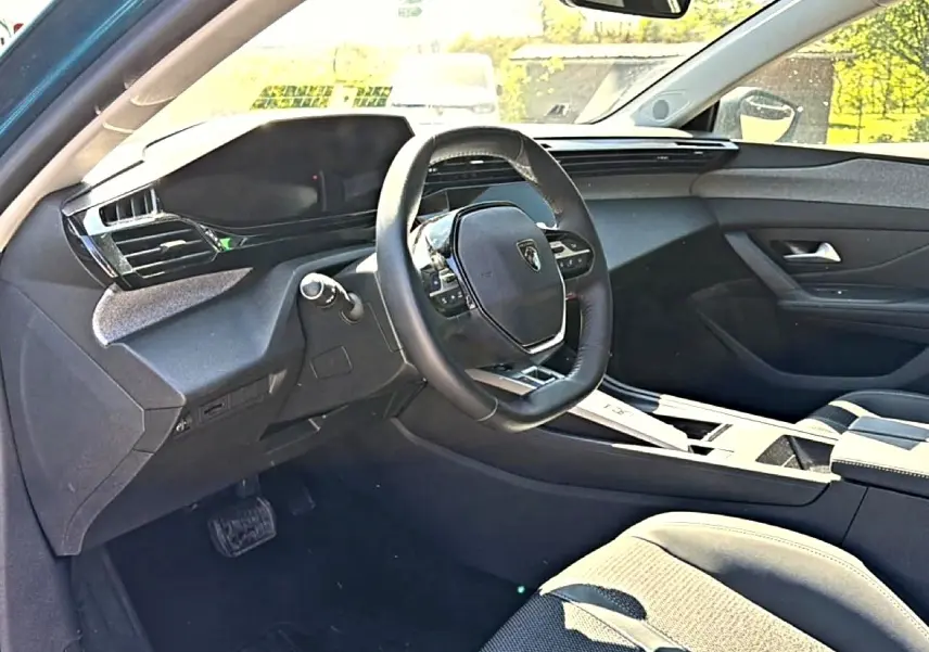 Intérieur de la Peugeot 408 Hybrid 145 allure e-dcs6 vue côté conducteur, volant cuir et tableau de bord moderne.