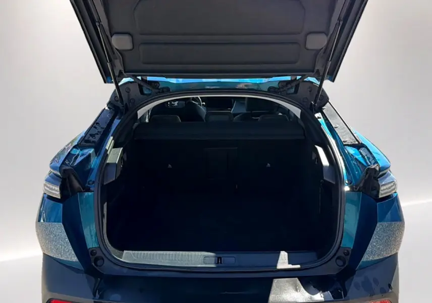 Coffre ouvert vu de l'arrière d'une Peugeot 408 Hybrid 145 allure e-dcs6 bleu, montrant l'espace de chargement vide.