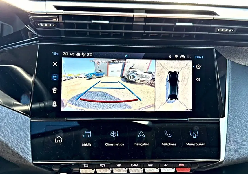 Vue rapprochée de l’écran tactile central du Peugeot 408 Hybrid bleu montrant la caméra de recul et l’aide au stationnement.