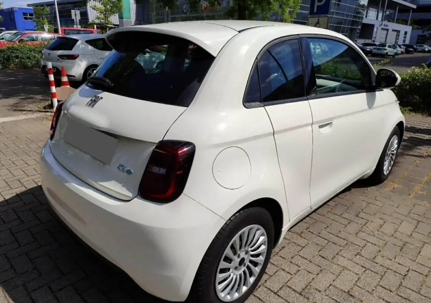 Vue 3/4 arrière droite d'une FIAT 500 électrique blanche avec feux arrière foncés et jantes multibranches.