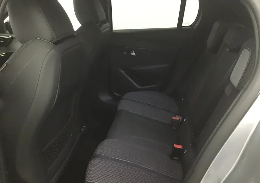 Vue intérieure sur les sièges arrière noirs et gris d'une Peugeot 208 1.2 PureTech 100 GT S&S 2023, porte ouverte côté droit.