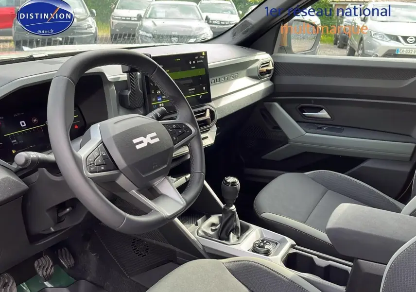 Intérieur avant du Dacia Duster 2025, version Journey, montrant le volant multifonction et la boîte manuelle.