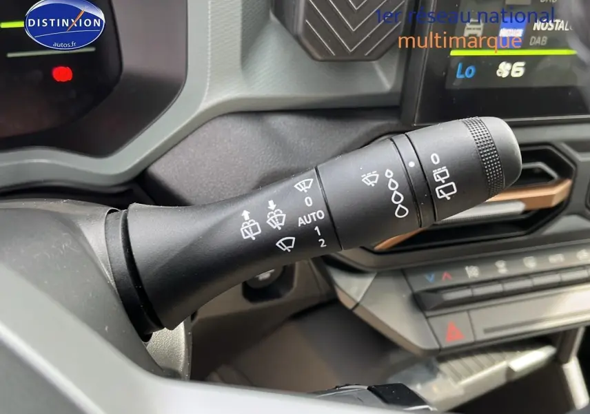 Gros plan sur la commande d’essuie-glace du Dacia Duster 2025 couleur Sandstone, intérieur moderne avec écran tactile.