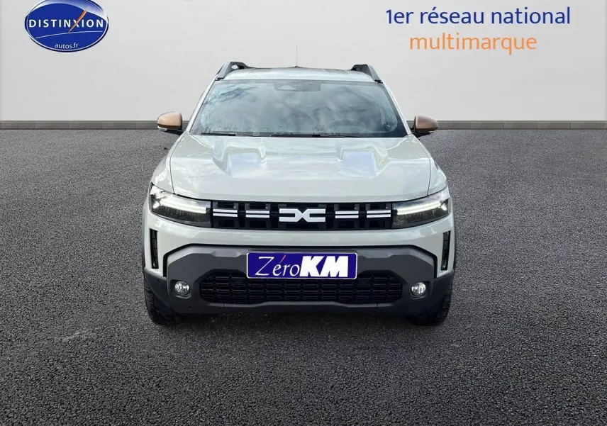 Vue frontale du Dacia Duster 2025 couleur Sandstone avec calandre noire et plaques Zero KM visible.