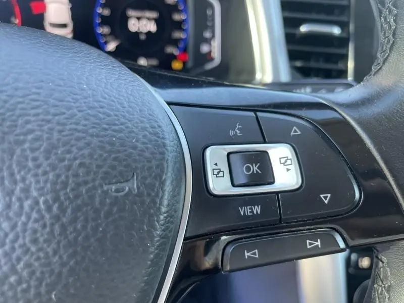 Gros plan sur les commandes multifonctions à droite du volant cuir du Volkswagen T-Roc gris foncé 2021, avec affichage numérique en arrière-plan.