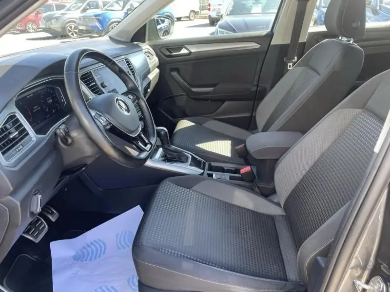 Intérieur du Volkswagen T-Roc 2021, vue côté conducteur, sièges tissu gris et tableau de bord moderne.