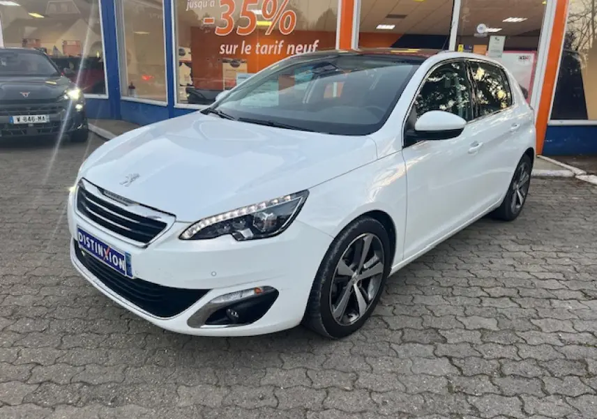 Peugeot 308 blanche vue 3/4 avant droit, toit panoramique en verre et jantes alliage distinctives visibles.