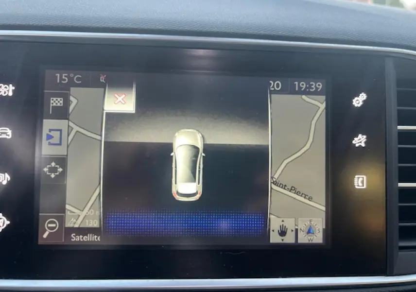 Écran tactile de navigation montrant une vue aérienne de la Peugeot 308 blanche avec carte routière environnante.