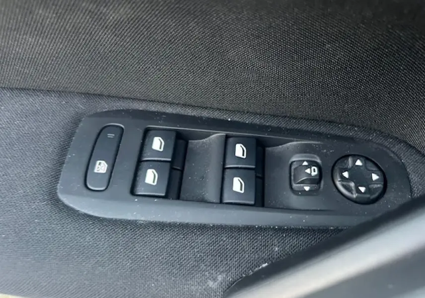 Panneau de commandes des vitres et rétroviseurs sur la porte côté gauche d'une Peugeot 308 blanche de 2017.