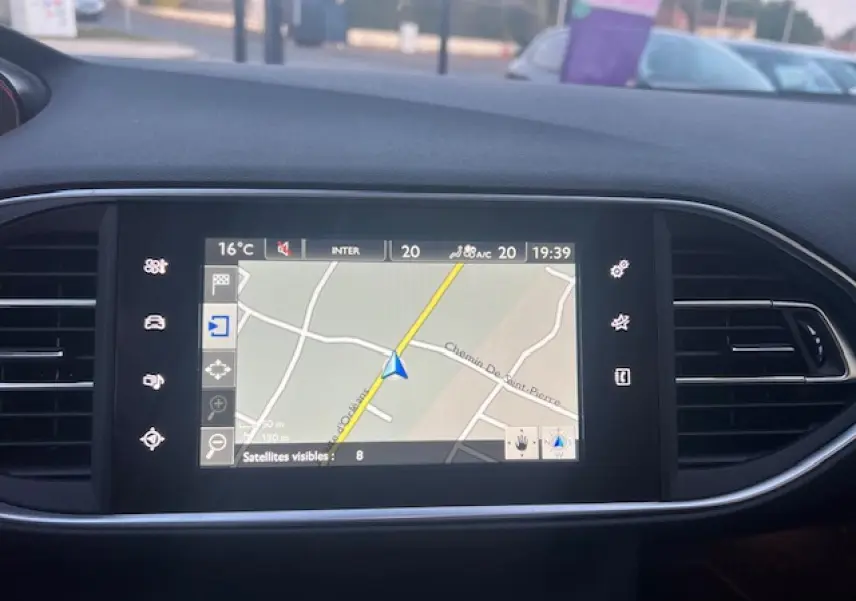 Écran tactile de navigation de la Peugeot 308 blanche, vue intérieure centrée sur la console centrale.