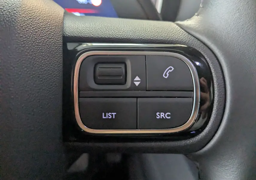 Gros plan sur les commandes gauche du volant du Citroën C5 Aircross gris platinium hybride 2024, boutons téléphonie et liste.