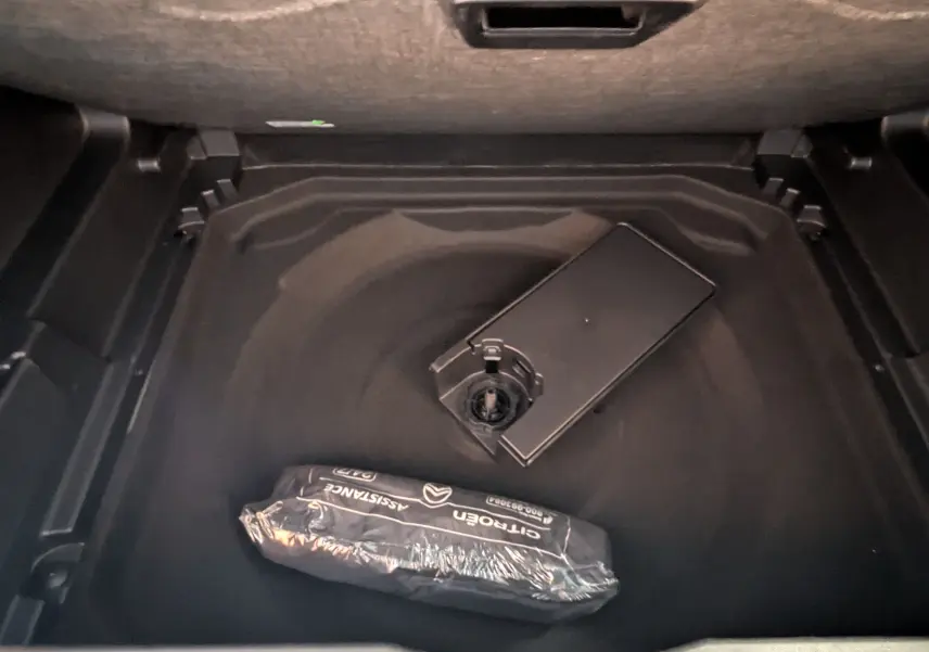 Coffre ouvert en vue plongeante du Citroën C5 Aircross hybride gris platinium montrant le rangement sous plancher.