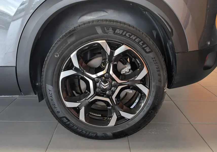 Vue latérale côté droit du Citroën C5 Aircross gris platinium, mettant en valeur la roue arrière et l'arche de roue noire.