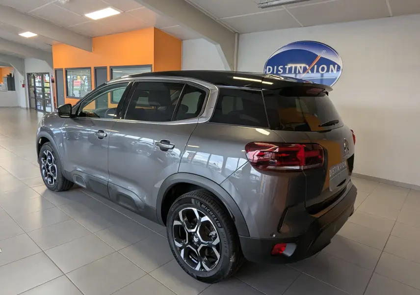 Vue 3/4 arrière droite du Citroën C5 Aircross hybride gris platinium avec toit noir et jantes alliage 18 pouces.