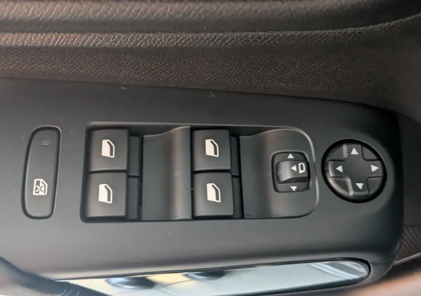 Gros plan sur les commandes de lève-vitres et réglages des rétroviseurs côté conducteur du Citroën C5 Aircross gris platinium 2024.