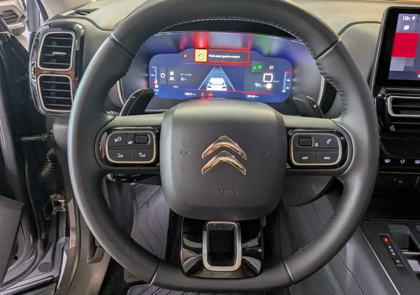 Volant cuir noir du Citroën C5 Aircross hybride 2024 avec commandes intégrées et tableau de bord numérique lumineux.