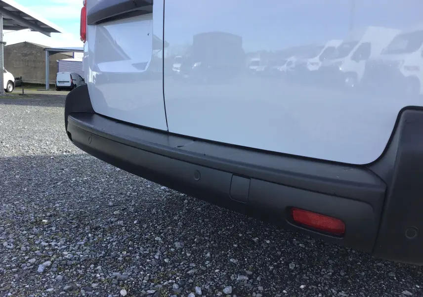 Gros plan sur le pare-chocs arrière noir du FIAT Scudo Fourgon blanc, avec capteurs de recul visibles.