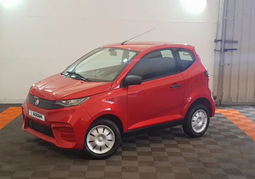 Vue 3/4 avant droite d'une Aixam Ambition 0.5 City Pack rouge avec rétroviseur caméra côté gauche en intérieur.