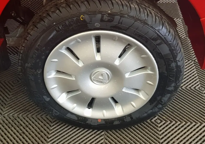 Gros plan sur la roue avant droite de l'AIXAM AMBITION rouge 2026 avec enjoliveur argenté et logo central visible.