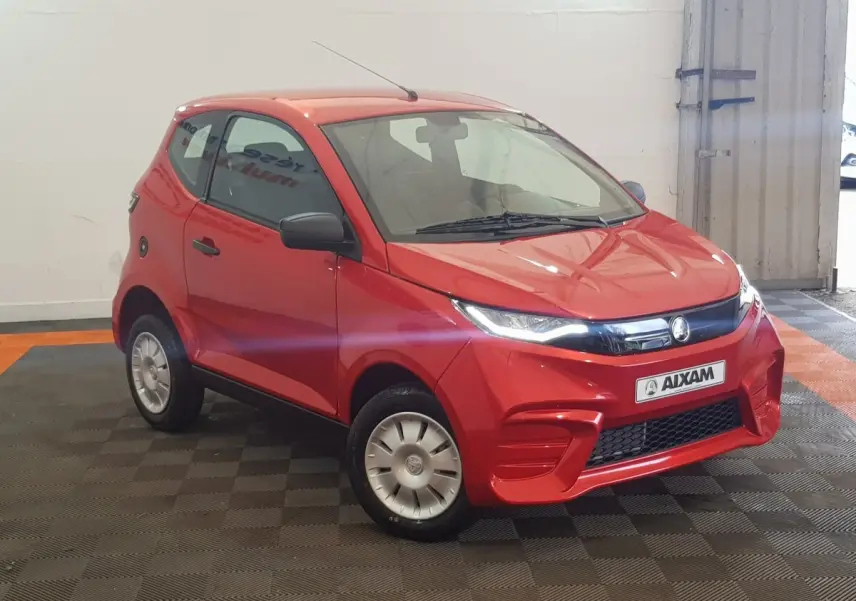Vue 3/4 avant droite d'une Aixam Ambition 0.5 City Pack rouge avec rétroviseur caméra côté gauche visible.