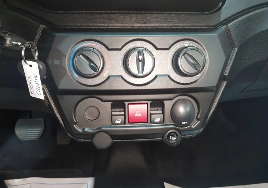 Vue rapprochée du tableau de bord noir de l'AIXAM AMBITION 0.5 CITY PACK 2026 avec commandes de climatisation et bouton rouge d'alerte.