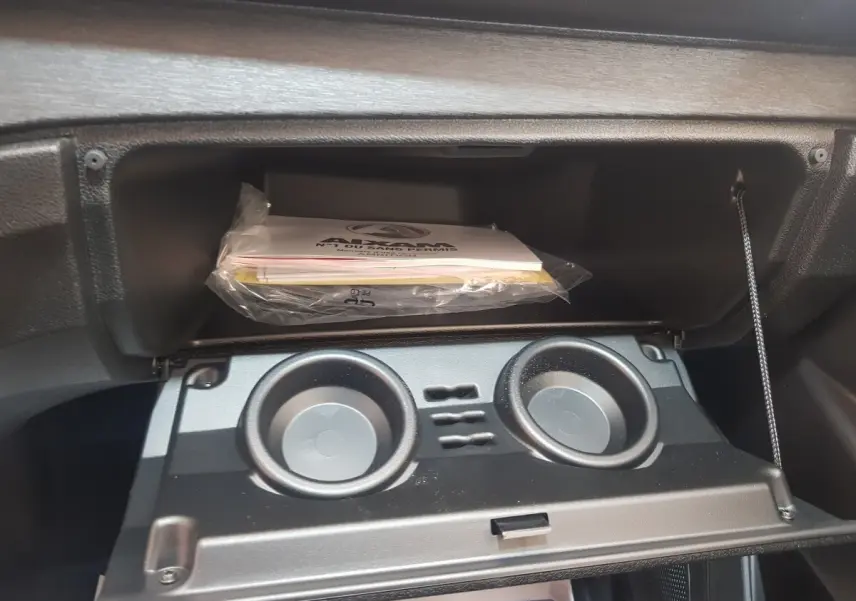 Intérieur de l'AIXAM AMBITION 0.5 CITY PACK 2026 montrant la boîte à gants ouverte avec porte-gobelets intégrés.