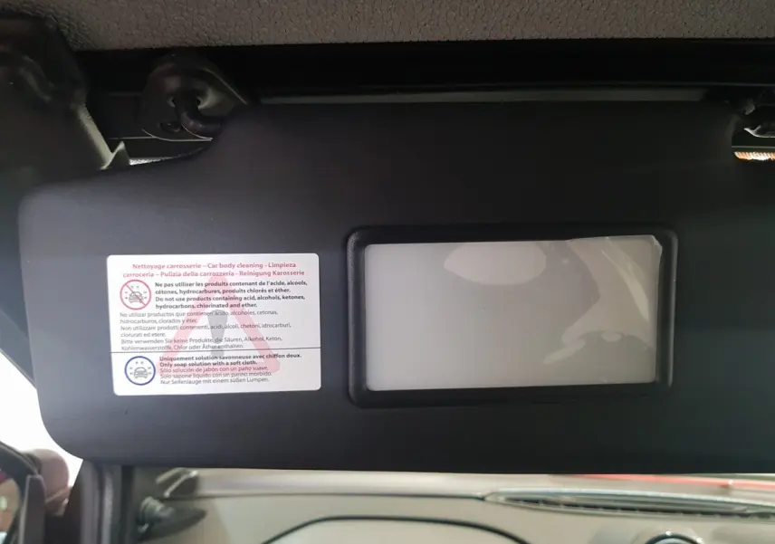 Intérieur de l'AIXAM AMBITION 0.5 CITY PACK 2026, vue sur le pare-soleil avec miroir et consignes de nettoyage.