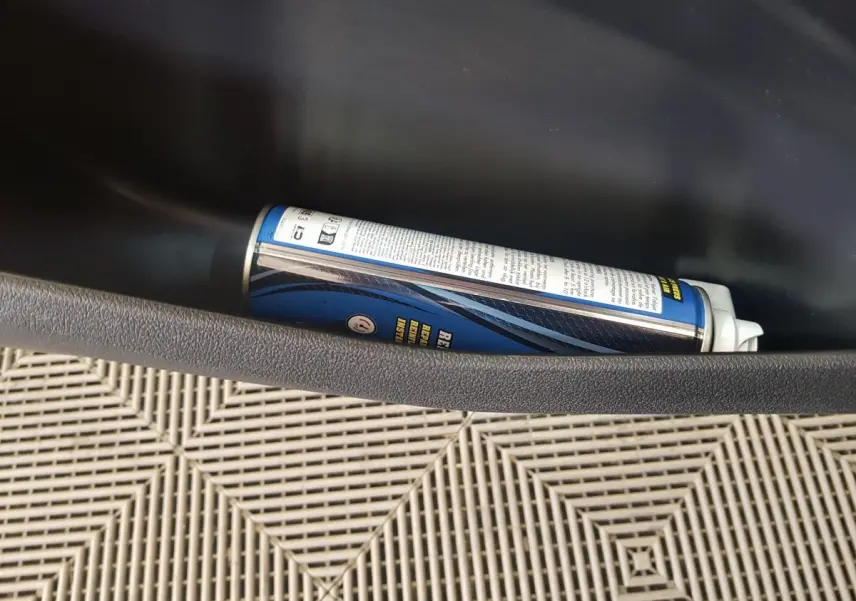 Gros plan sur la porte côté conducteur de l'AIXAM AMBITION 0.5 CITY PACK rouge, montrant le rangement intérieur avec un spray.