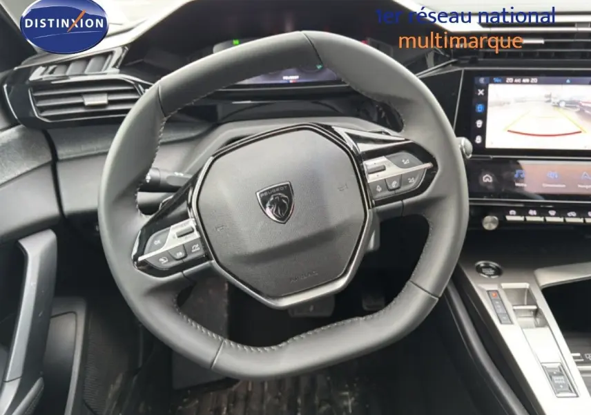 Vue intérieure centrée sur le volant cuir noir et la console centrale high-tech de la Peugeot 308 hybride 2025.