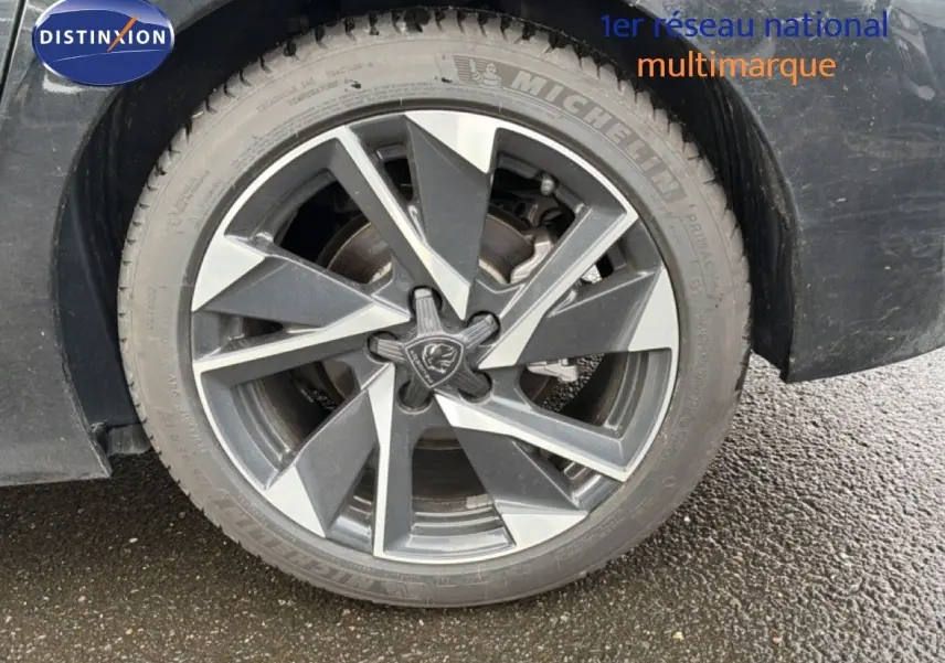 Gros plan sur la roue avant droite noire métal d'une Peugeot 308 1.2 Hybrid 145ch avec jante alliage distinctive.