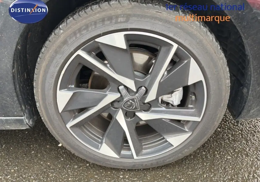 Gros plan sur la jante alliage bicolore de la Peugeot 308 noire, mettant en valeur le logo lion central.