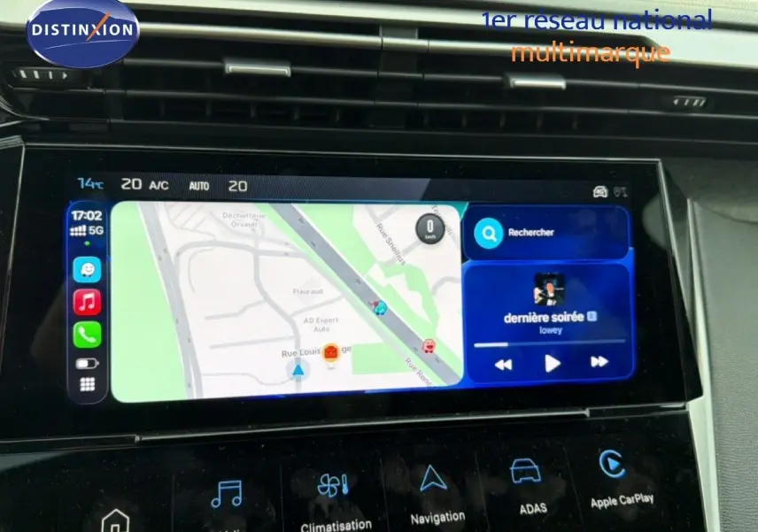 Écran tactile central de la Peugeot 308 noire hybride 2025 affichant navigation et musique, vue intérieure du tableau de bord.