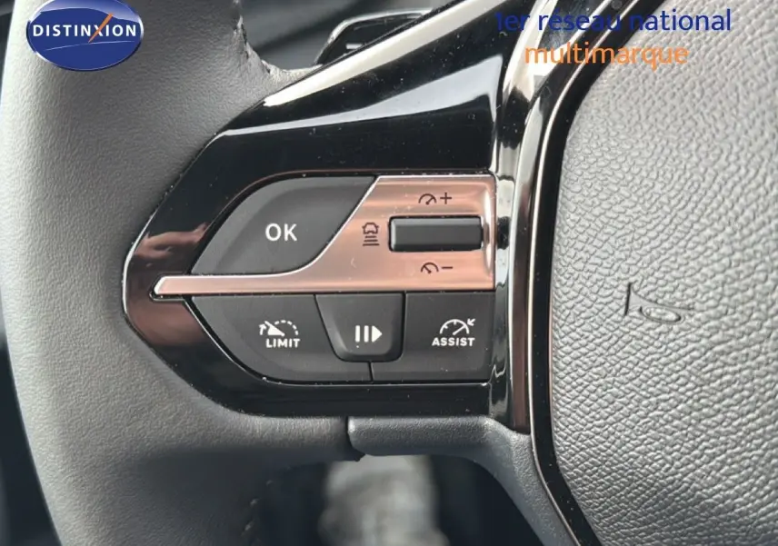 Gros plan sur les commandes au volant noir de la Peugeot 308 1.2 Hybrid 145ch Allure, avec boutons de limitation et assist.