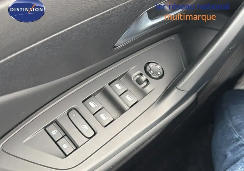 Gros plan sur les commandes des vitres électriques et rétroviseurs sur la porte côté gauche d’une Peugeot 308 noire hybride 2025.